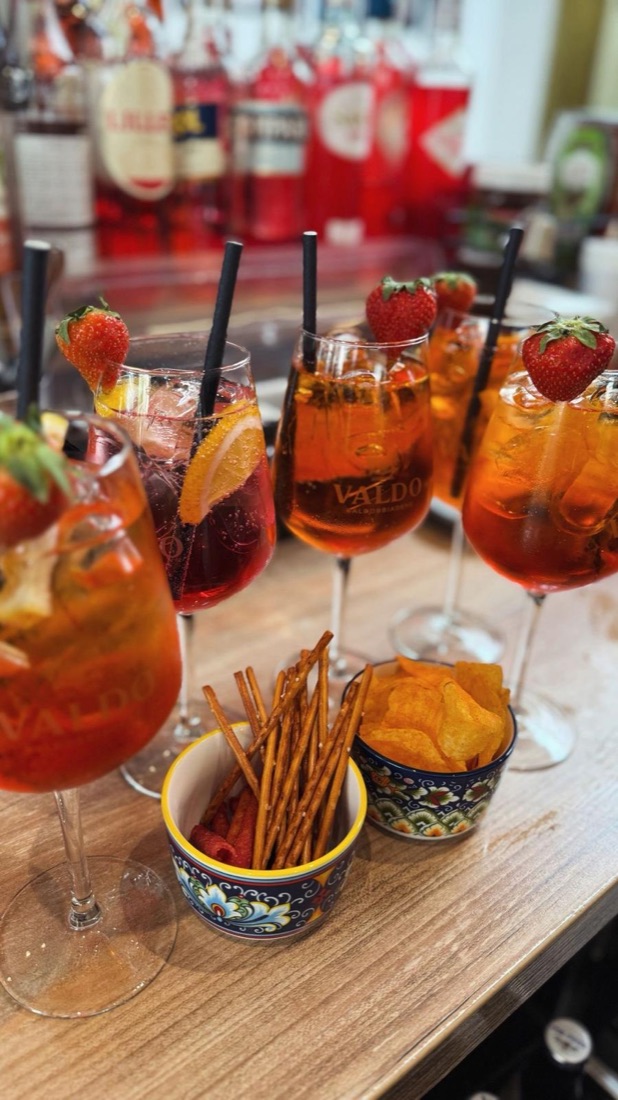Verschiedene Spritz-Drinks mit Erdbeeren, dazu Salzstangen und Chips